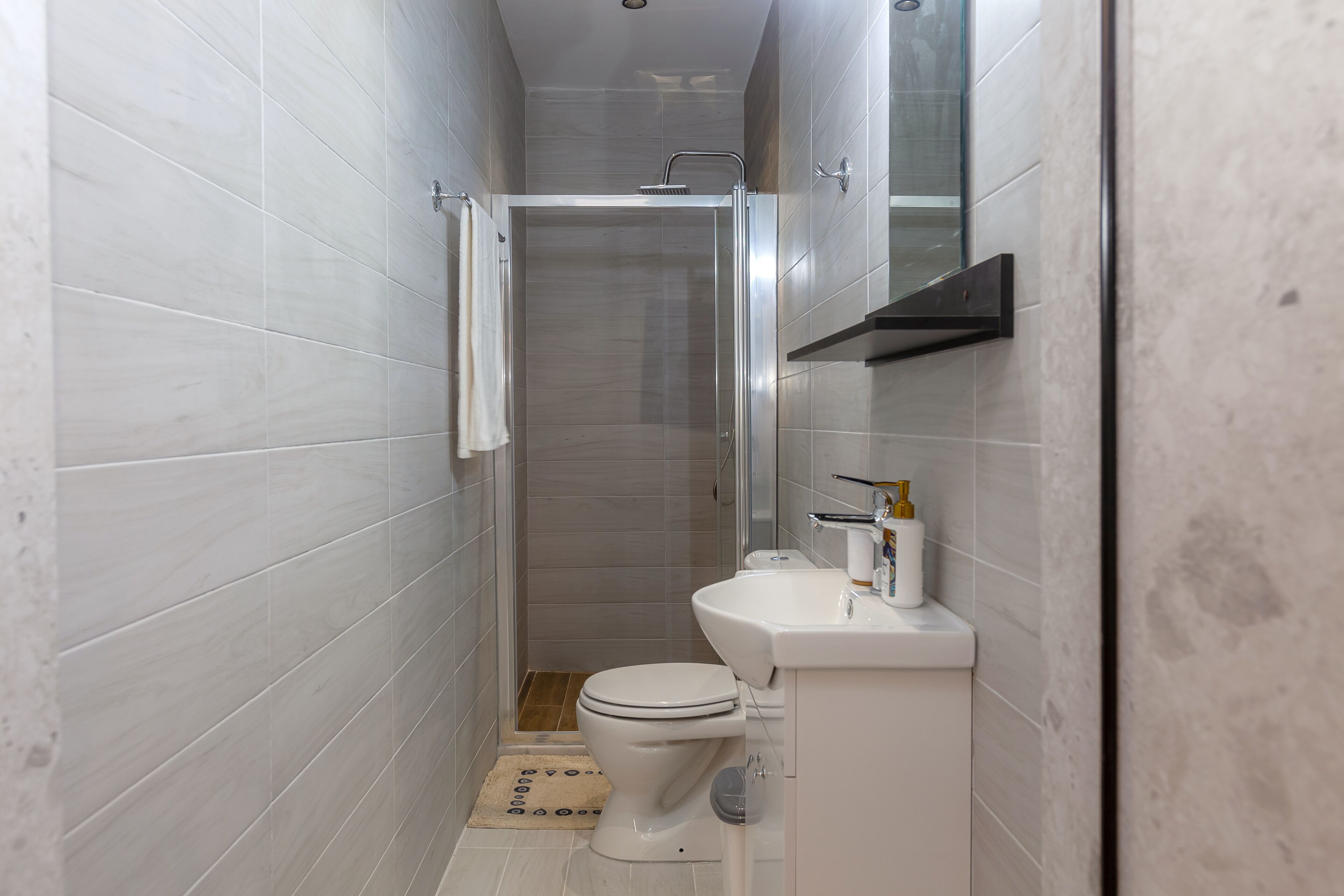 Une salle de bain moderne avec une douche à parois de verre, des toilettes blanches et un lavabo avec un miroir au-dessus.