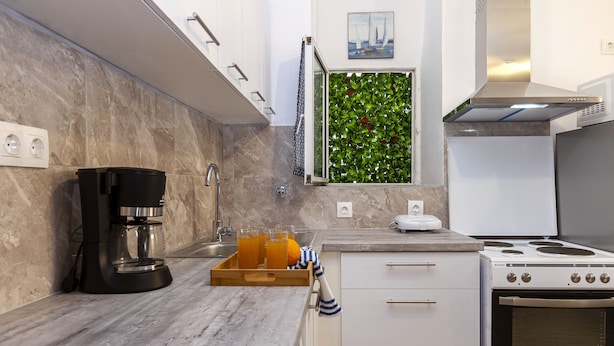 A modern kitchen with a coffee maker, a fruit tray, and a stove. - Navy Blue Apartment (Corfu)