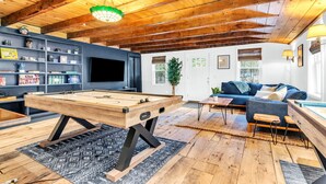 Un salon chaleureux avec une table de billard, un canapé bleu et un téléviseur.