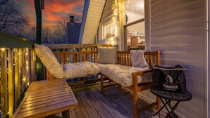 Une terrasse extérieure accueillante, avec un banc en bois, un fauteuil de relaxation, une petite table et un sac posé sur une chaise.