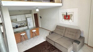 A two-story apartment with a kitchenette on the ground floor, a sofa, and a brown rug. - Saint Sebastian Flat 602Duplex no Centro (Jaragua do Sul)