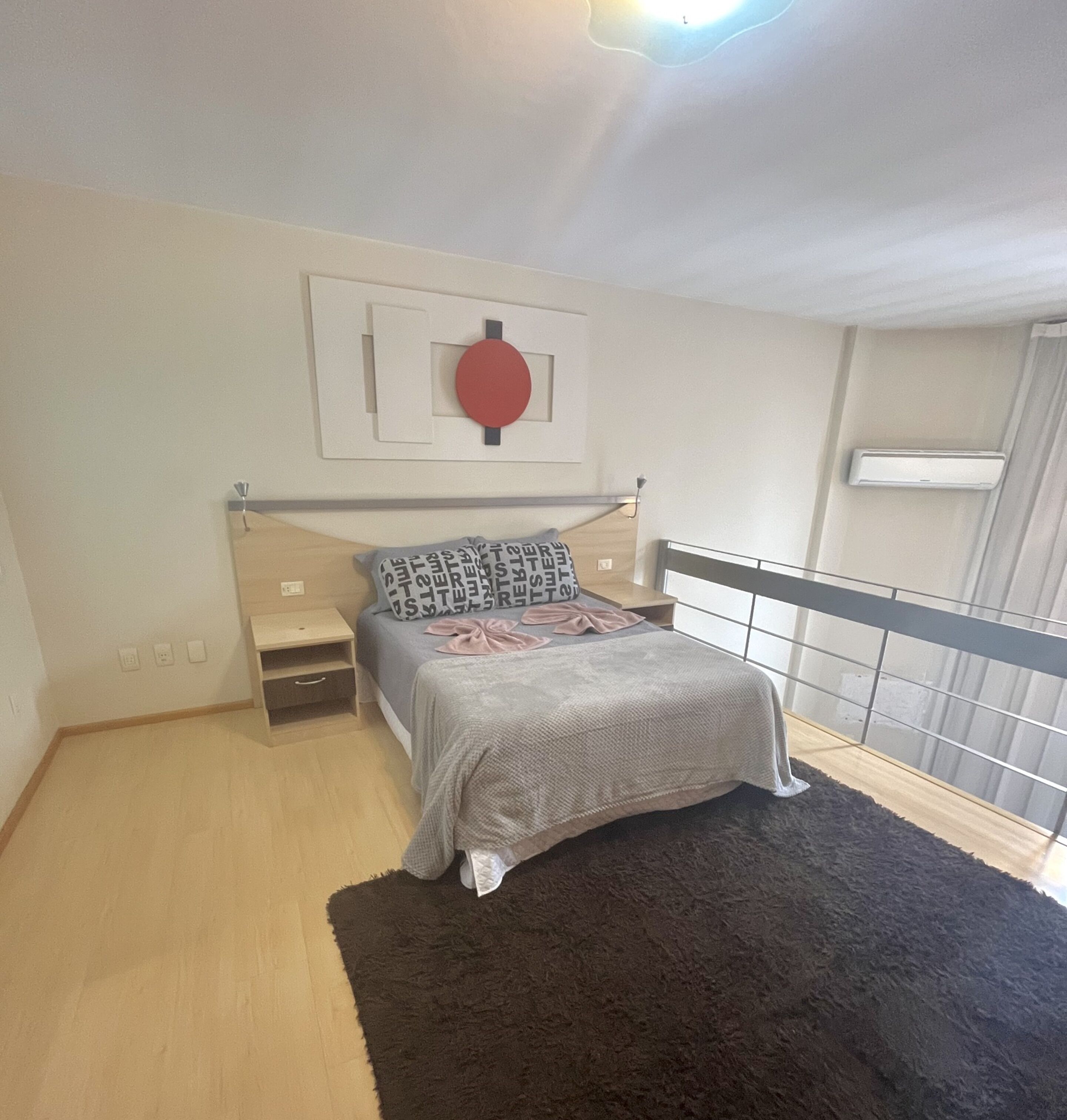 A bedroom with a bed, bedside table, and a wall-mounted light fixture.