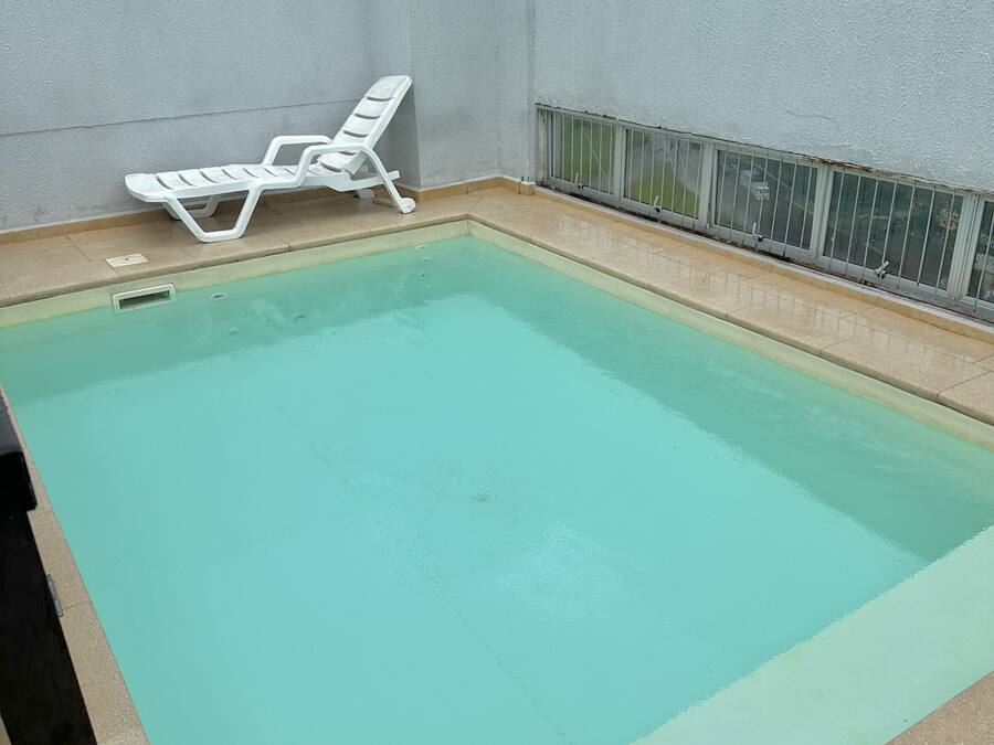 A rectangular swimming pool with a white lounge chair beside it.