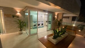 A modern hotel entrance with glass doors, a reception desk, and a small indoor garden. - Edifício Promenade II Apt 306 (Maceió)