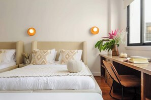 Une chambre à coucher comprenant un lit, des tables de chevet, un bureau et une chaise.