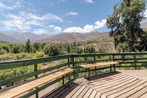 A wooden deck with benches overlooking a mountainous landscape.