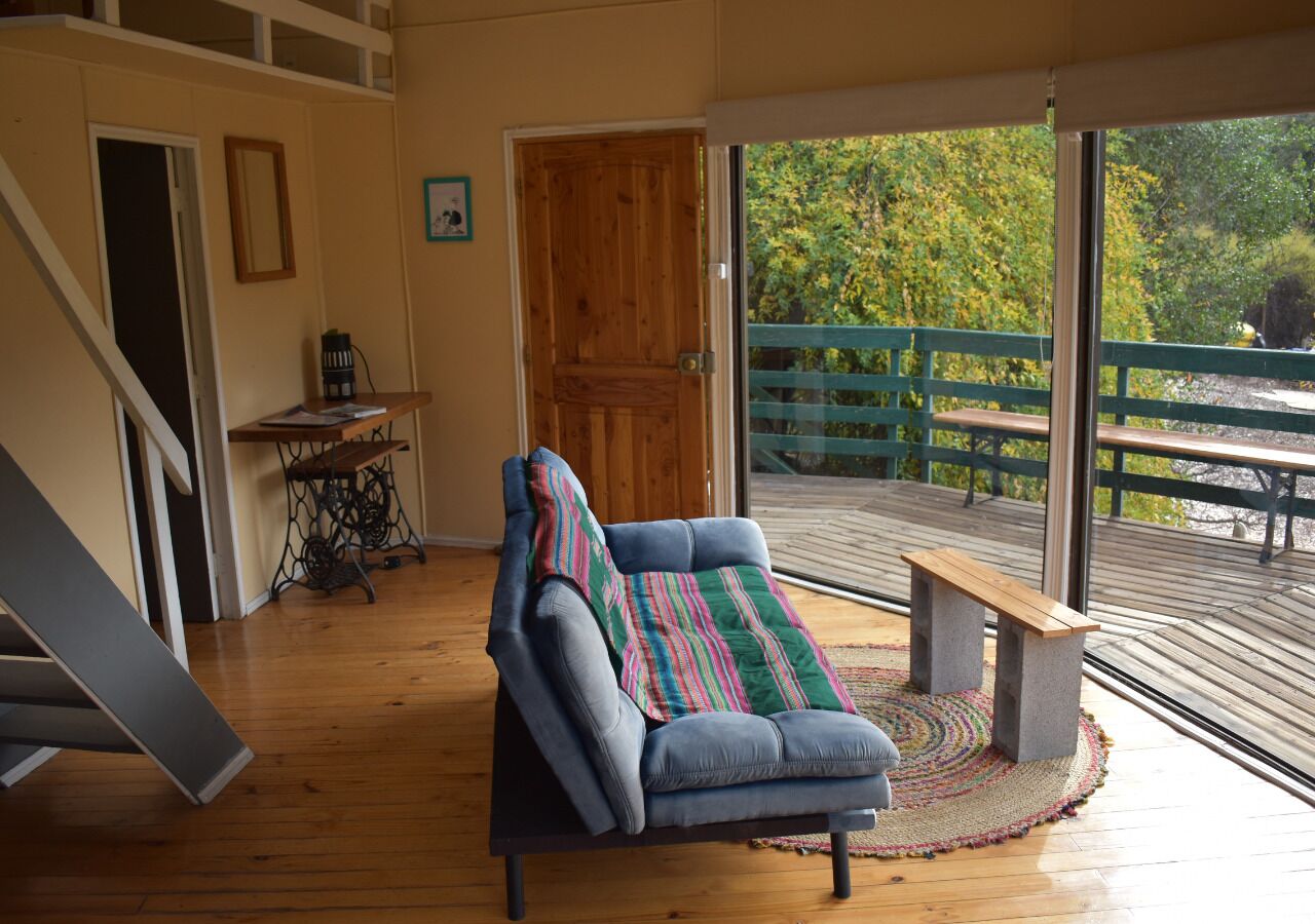 Ein gemütliches Zimmer mit einem blauen Sofa, einer Holztür und Blick auf eine Terrasse mit Geländer.