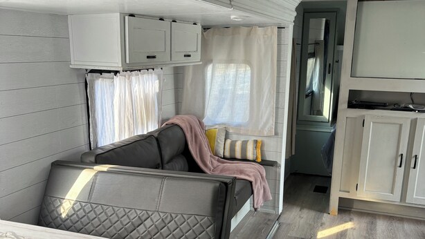 Un intérieur de camping-car compact comprenant un canapé, une petite table et un coin cuisine.
