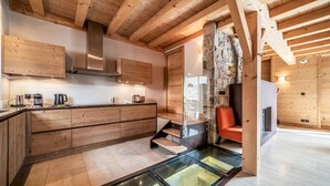 Een moderne keuken met houten keukenkastjes, een eiland met glazen blad en een accentmuur van steen.