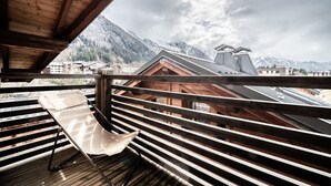 Een houten balkon met uitzicht op besneeuwde bergen en gebouwen.