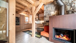 Een moderne keuken met houten balken, een stenen openhaard en een glazen deur naar een eethoek.