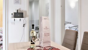 Une chambre d’hôtel avec une table en bois, une bouteille de vin, deux verres à vin, un sac pour la dégustation de vin et un lit avec un cadre en métal.