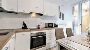 Une cuisine moderne avec des meubles blancs, un four encastré, un four à micro-ondes et un coin repas comprenant une table et des chaises.