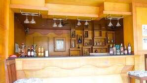 Una zona de bar con estantes de madera, lámparas colgantes y taburetes.