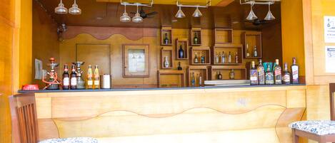 Un espace bar avec des étagères en bois, des luminaires suspendus et des tabourets de bar.