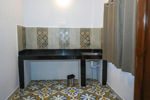 A small kitchen with a black countertop, a sink, and patterned floor tiles.