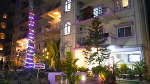 Un edificio de varios pisos con balcones, un letrero que dice 'RESERVED PARKING' y plantas en macetas.