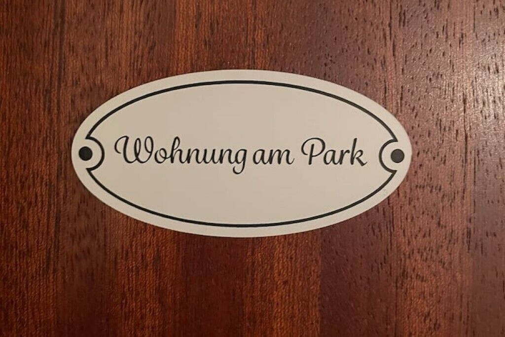 A wooden surface with an oval-shaped sign that reads "Wohnung am Park".