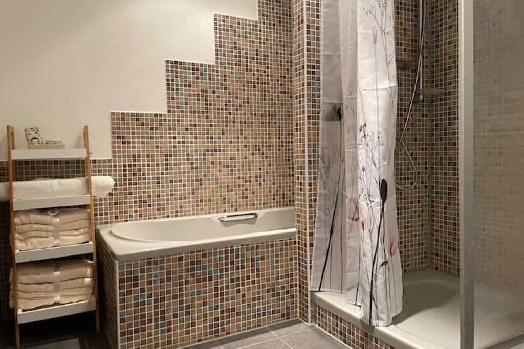 A bathroom with a tiled wall, a bathtub, a shower curtain, and a towel rack.