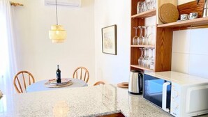 Een keuken met een granieten aanrecht, een magnetron en een eethoek met stoelen en een tafel.