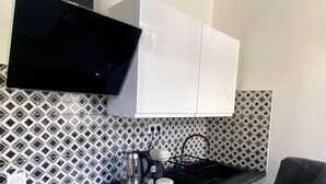 A modern kitchen with black countertops, white cabinets, and a black chair. - 􏰇􏰅􏰱􏰂􏰄􏰎􏱂􏰳􏱃 􏰄􏰁􏰁􏰂􏰅􏰇􏰁􏱂􏰃􏱃appartement Dans le Centre Historique (Lourdes)