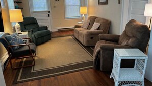 A living room with a green armchair, a brown sofa, and a white side table.