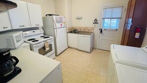 A compact kitchen with white appliances, a microwave, stove, refrigerator, and a sink.