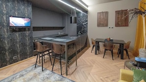 A modern kitchen with a marble countertop, bar stools, and a flat-screen TV mounted on the wall. - Elegant and luxurious apartment for 6 people, in the heart of Turin (Torino)