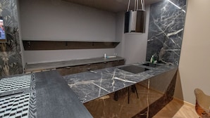 A modern kitchen with a marble countertop, a built-in sink, and a hanging light fixture. - Elegant and luxurious apartment for 6 people, in the heart of Turin (Torino)
