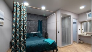 A bedroom with a four-poster bed, a bathroom with a sink and mirror, and a door leading to another room. - Elegant and luxurious apartment for 6 people, in the heart of Turin (Torino)