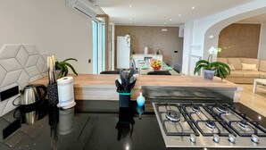 Una cocina moderna con estufa a gas, cafetera y refrigerador al fondo.