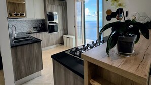 Una cocina moderna con una isla central, electrodomésticos integrados y vistas al exterior.