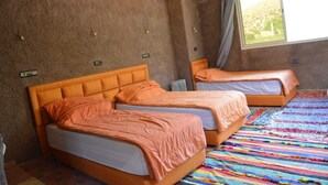 A room with two beds, a window with a view, and a colorful striped rug. - Riad Dar Tagine (Asni)