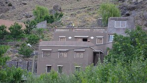 A two-story building with multiple windows and balconies, surrounded by greenery and a hilly landscape. - Riad Dar Tagine (Asni)