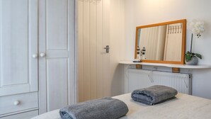 Un baño con una puerta blanca, un espejo con marco de madera, un radiador y dos toallas en el suelo.