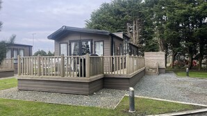 A modern, two-story mobile home with a deck and a fenced patio area. - Cosy 3-bed hot tub Lodge in Pr3 (Preston)