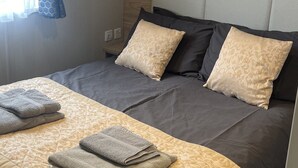 A neatly made bed with a quilted headboard, two pillows, and folded towels. - Cosy 3-bed hot tub Lodge in Pr3 (Preston)