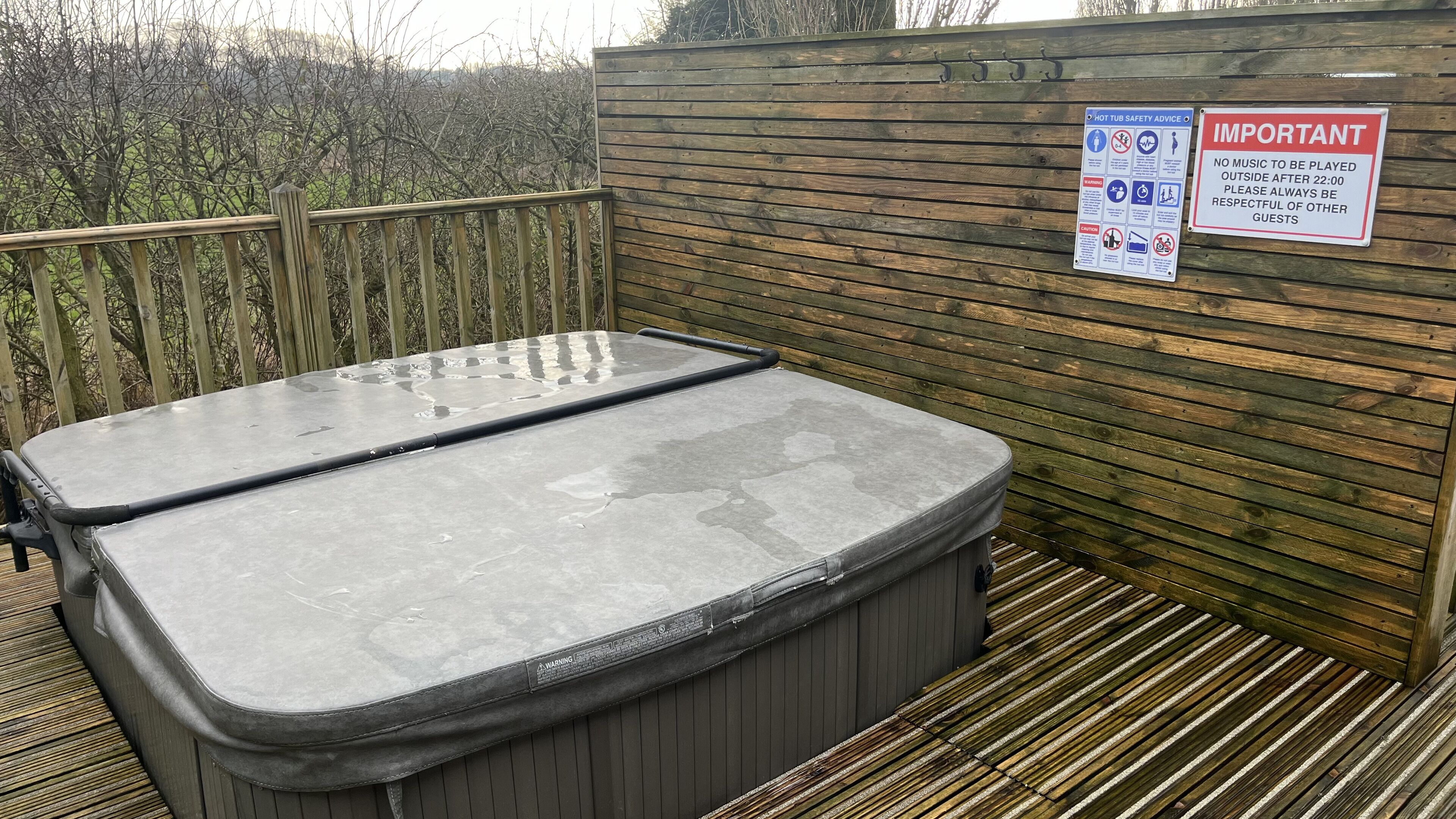A hot tub with a wooden deck and a wooden fence in the background.