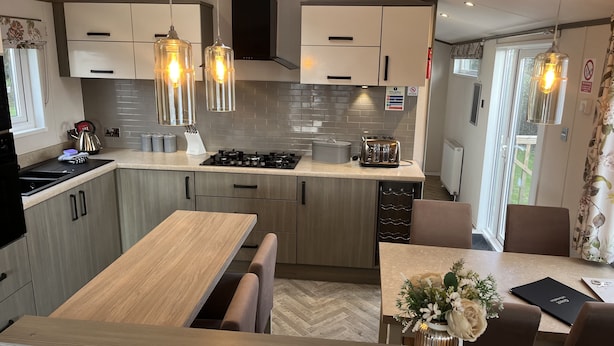 Una cocina moderna con armarios de madera, una estufa a gas y una zona de comedor con banco y mesa.