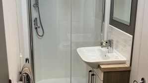 Un baño moderno con cabina de ducha de vidrio, lavamanos con espejo y retrete.