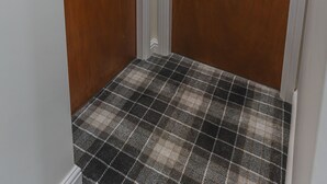 Zwei Holztüren mit den Nummern 3 und 2, ein Schachbrettteppich und weißes Zierleistenwerk.
