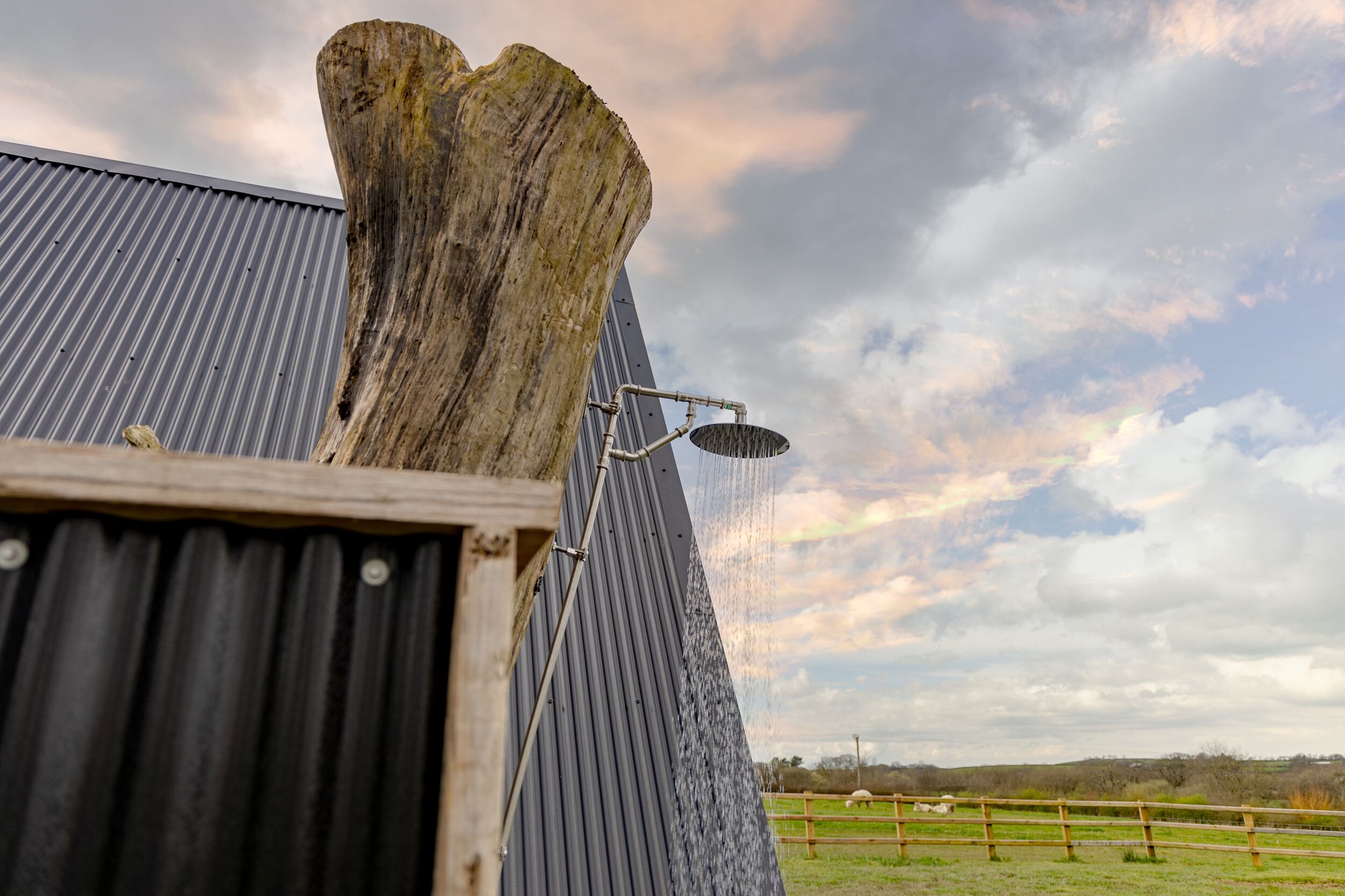 A corrugated metal structure with a wooden post and a water spout.