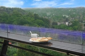Desayuno preparado en un balcón con vistas a un paisaje boscoso.