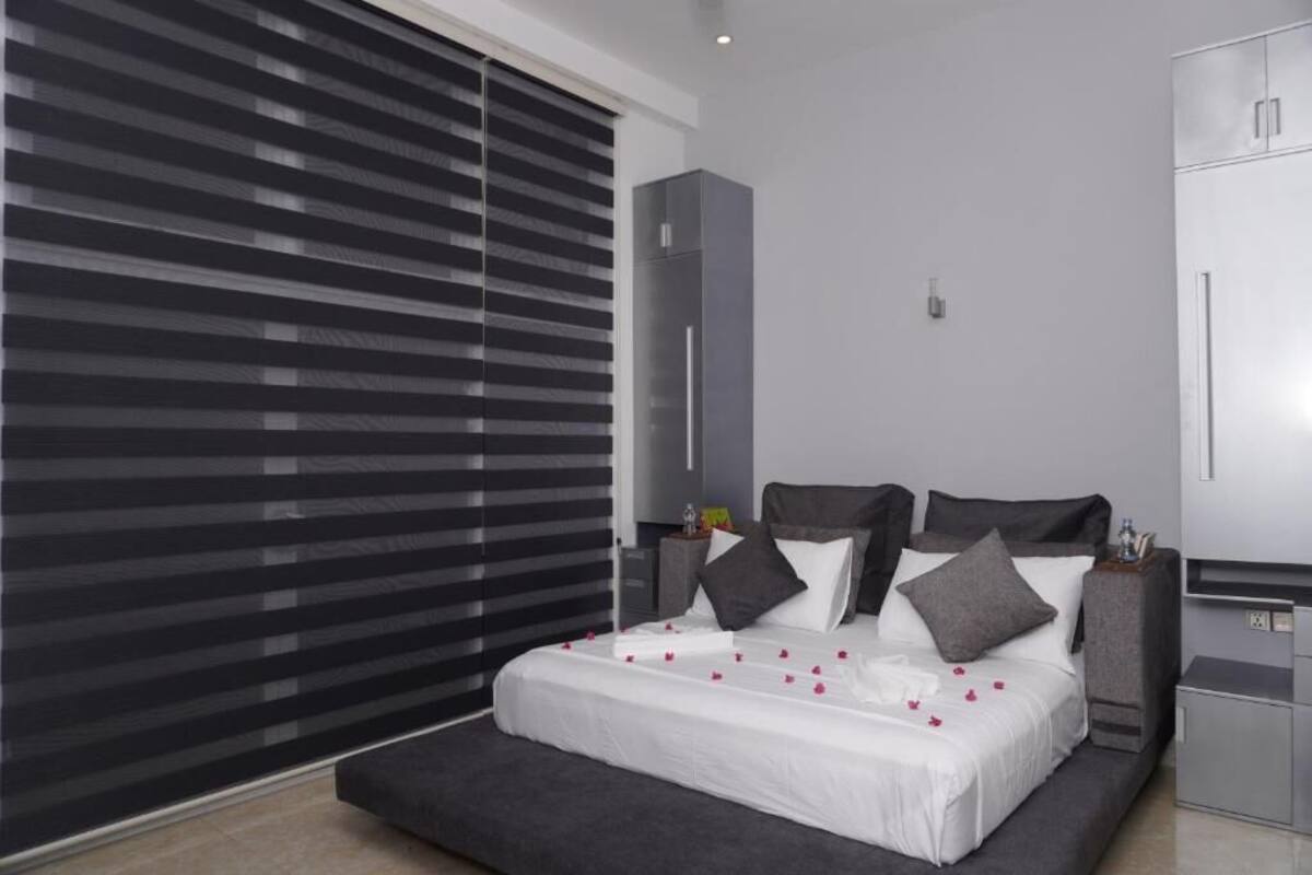 A modern bedroom with a large bed, a nightstand, a wardrobe, and a sliding door.