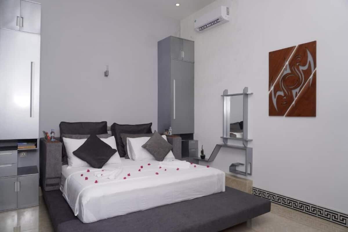 A modern bedroom with a bed, bedside tables, a wardrobe, and a large mirror.