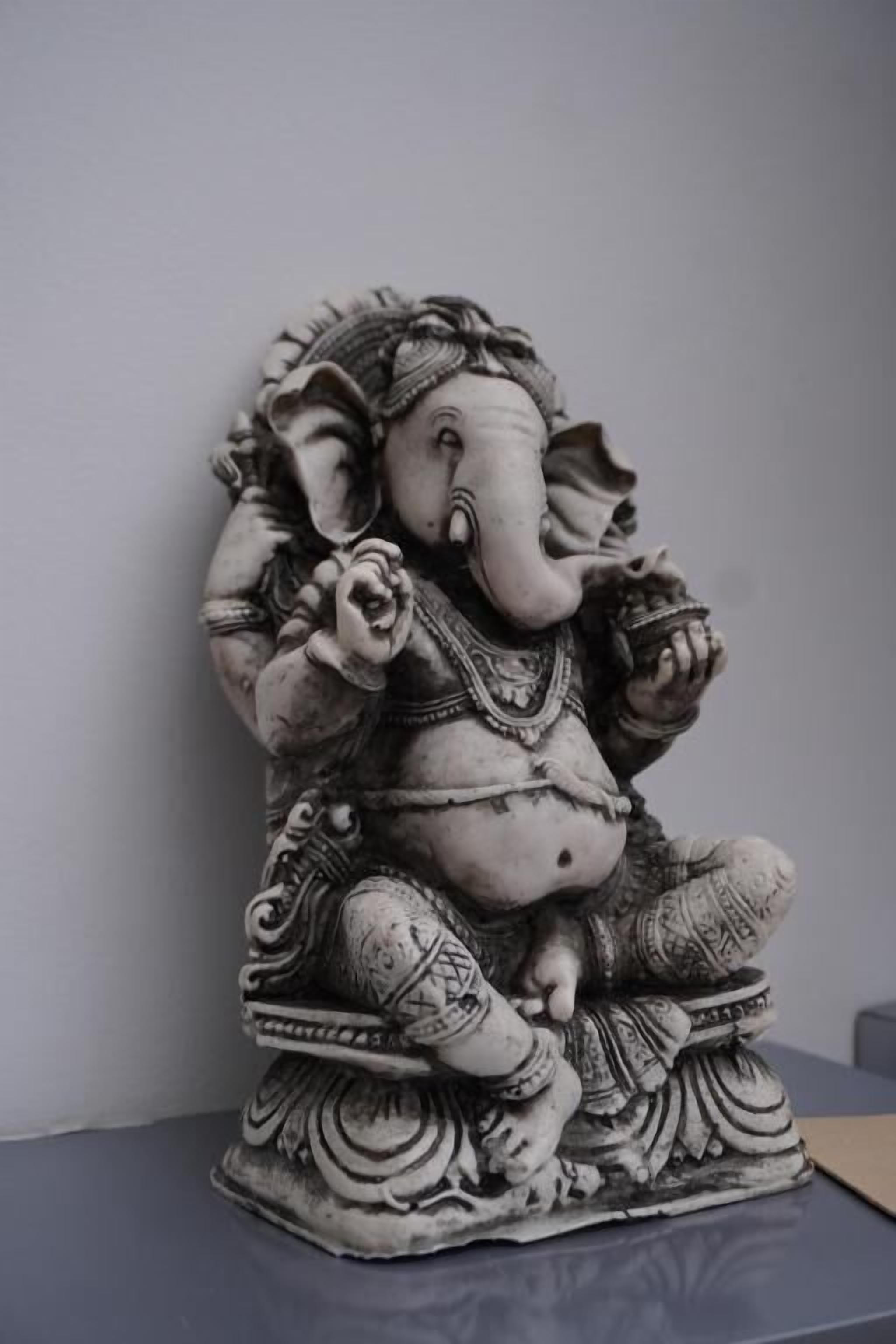 A detailed sculpture of a deity with intricate patterns and jewelry, placed on a pedestal.