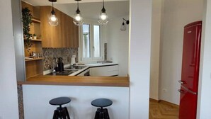A kitchen with wooden cabinets, a red refrigerator, and two bar stools. - Green Heart Terrace - Newly renovated attic in the historic center of Narni (Narni)