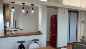 A compact kitchen with a wooden countertop, a red refrigerator, and a dining area with a table and two chairs. - Green Heart Terrace - Newly renovated attic in the historic center of Narni (Narni)