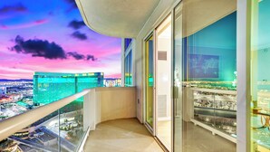 Un balcón con vista a la ciudad, puertas de vidrio y barandilla.