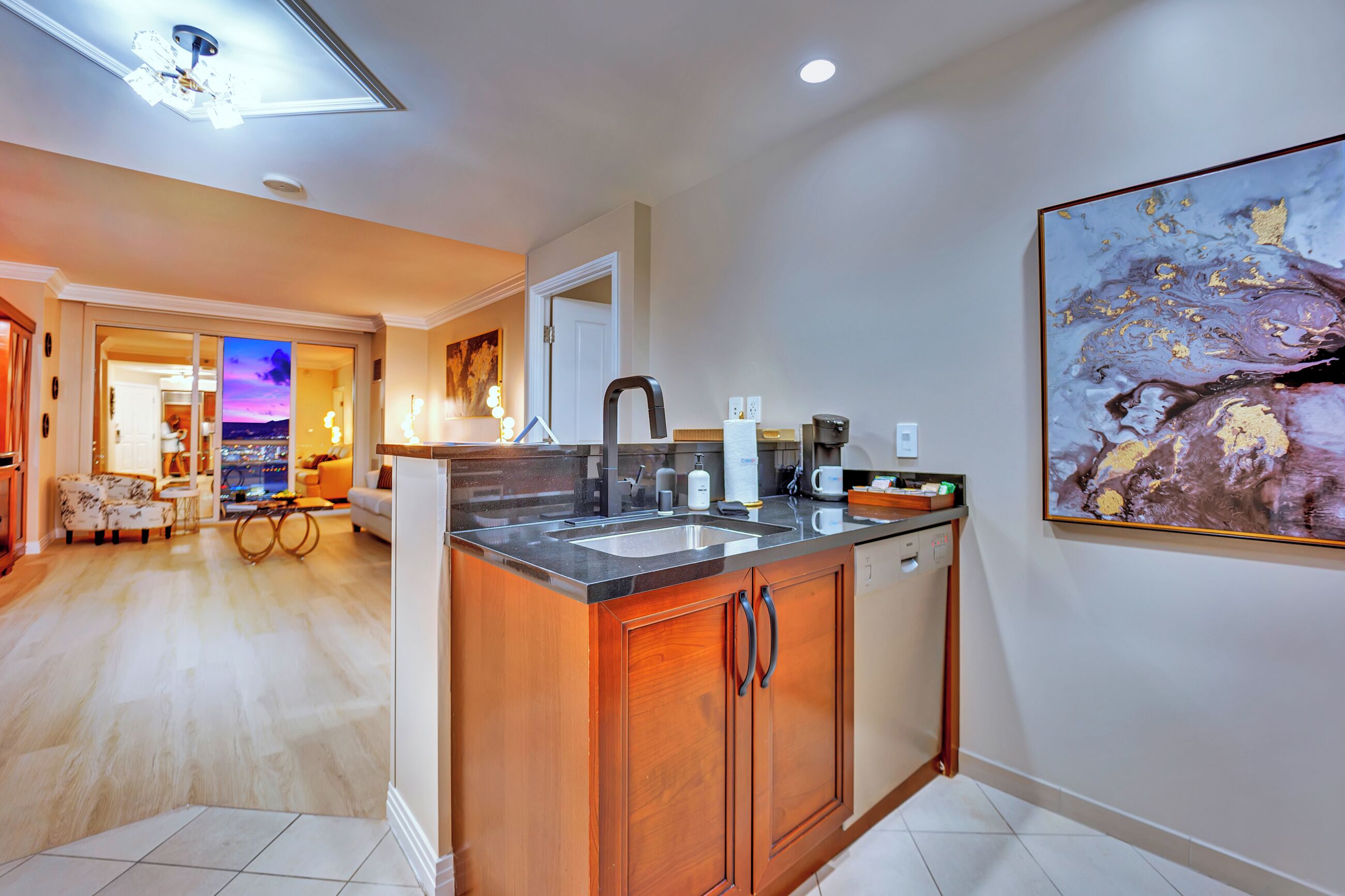 A modern kitchen with a central island, a dishwasher, and a dining area with a view.